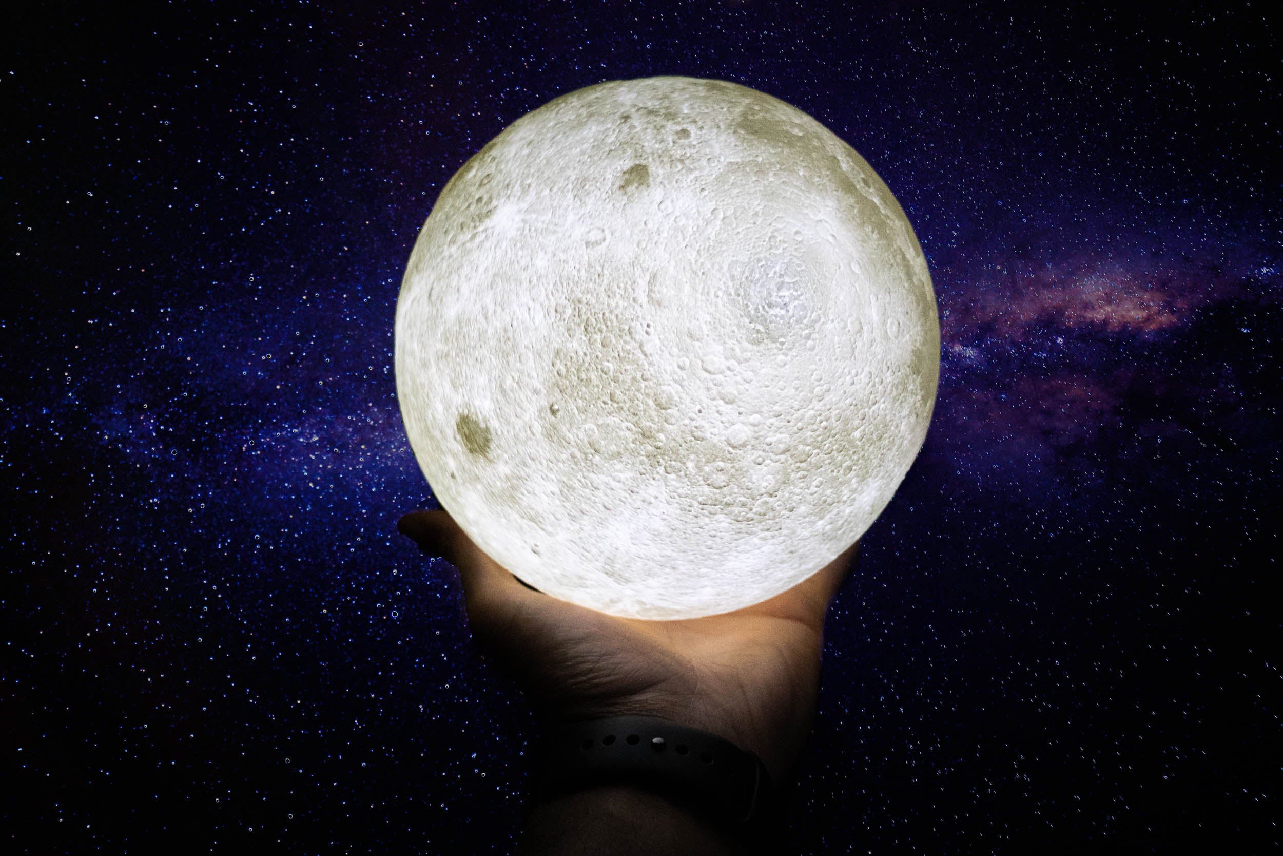 moon in the palm of a hand with the galaxy behind it